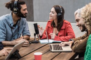 Group of people record radio podcast together - Young friends talk during live stream session